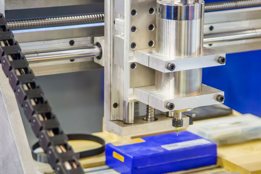 CNC-gravyrmaskin med 3-axligt linjärsystem med kulskruv som bearbetar plastdetalj.